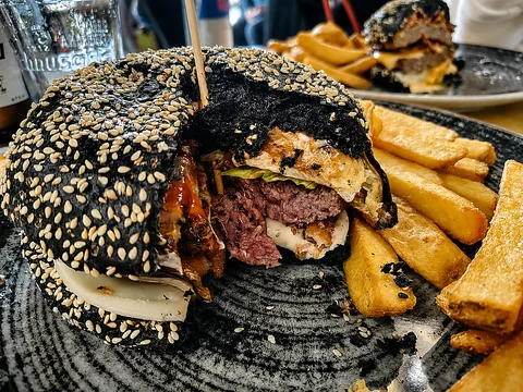 Burger con pane nero tagliato a metà con patatine fritte