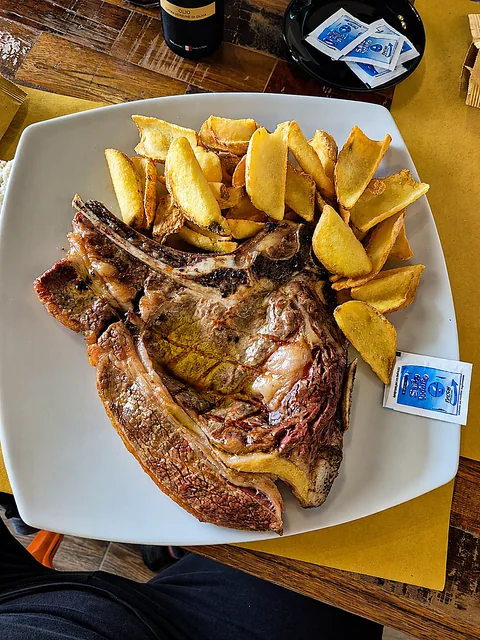 Bistecca con l'osso alla brace servita con patate arrosto